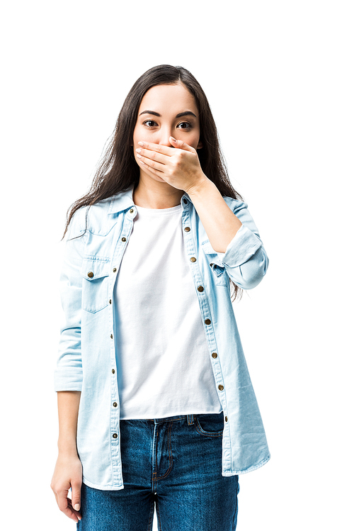 attractive and shocked asian woman in denim shirt obscuring face isolated on white