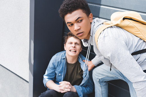 selective focus of african american boy in hoodie and jeans bulling screaming and scared boy