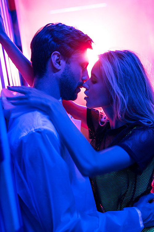 side view of attractive and blonde woman hugging and kissing with ...