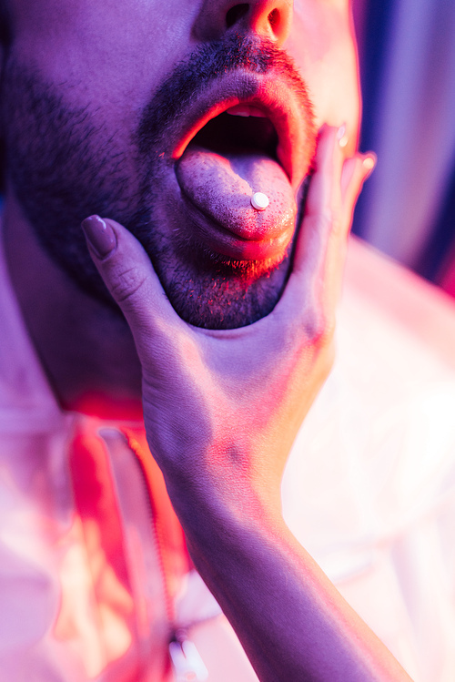 cropped view of man with LSD on tongue and woman touching his face