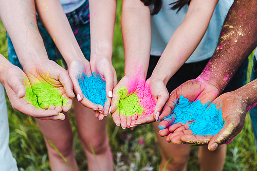 cropped view of multicultural friends holding colorful holi paints in hands