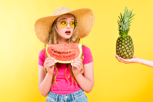 beautiful surprised girl in Straw Hat with watermelon looking at pineapple On yellow