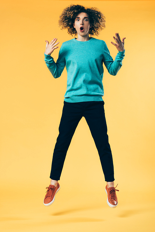 shocked curly teenager jumping on yellow