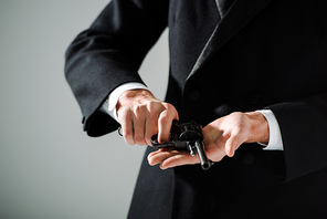 cropped view of gangster in formal wear holding black gun isolated on grey