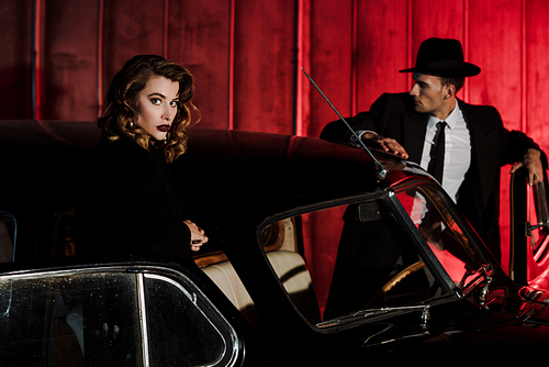 selective focus of attractive woman standing near retro car and man in hat