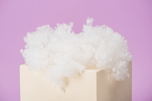 white fluffy cloud made of cotton wool on cube isolated on violet background