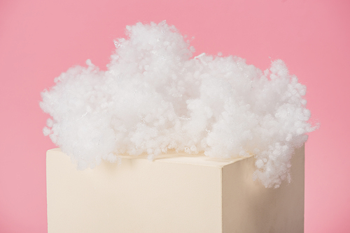 white fluffy cloud made of cotton wool on cube isolated on pink background