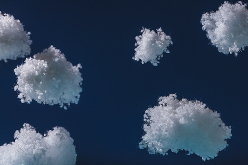 white fluffy clouds made of cotton wool isolated on dark blue