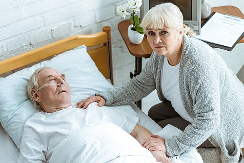 overhead view of sad senior woman and man in coma in hospital