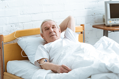 sick senior man on bed in ward in clinic