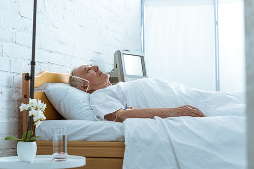 sick senior man on bed in ward in clinic