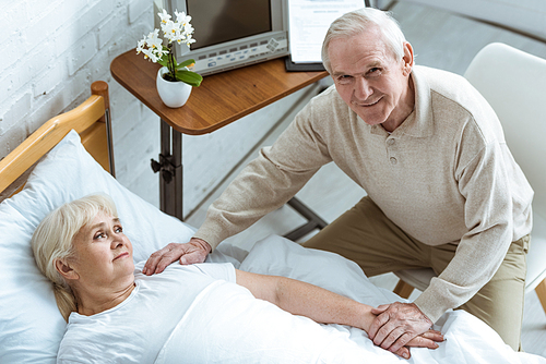 overhead view of sick senior woman with husband in clinic