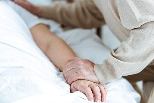 partial view of senior sick woman with husband in clinic