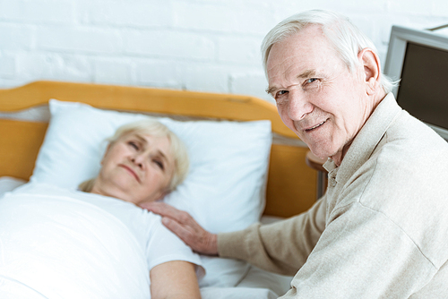 smiling senior man with sick wife in clinic