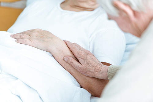 partial view of sick senior woman with husband in hospital