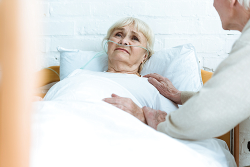 partial view of senior man with sick wife in hospital