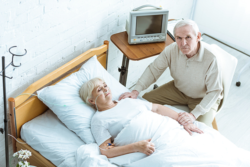 overhead view of sick senior woman with husband in clinic