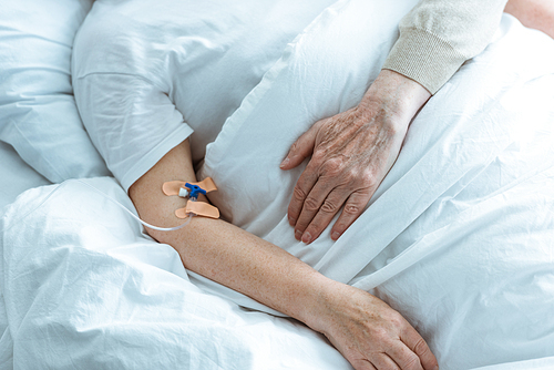 partial view of sick senior woman with husband in hospital