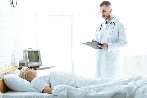 doctor with clipboard and sick senior woman lying on bed