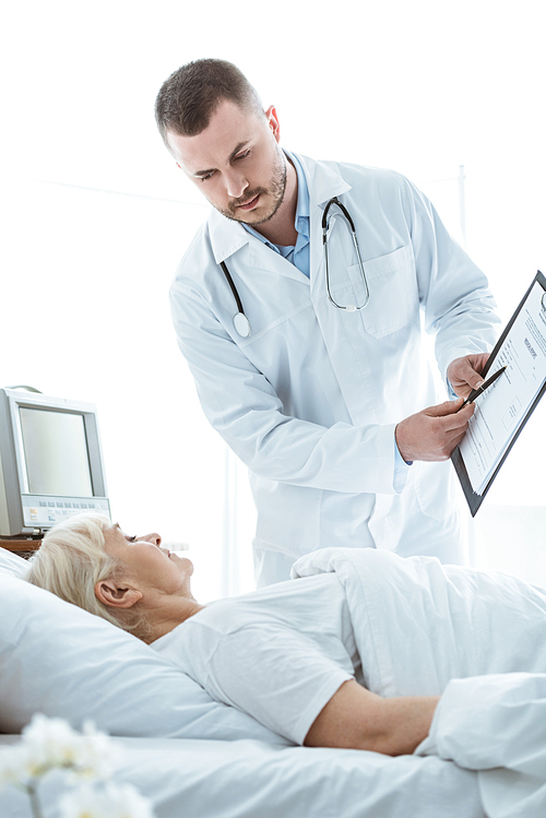 doctor with clipboard and sick senior woman lying on bed