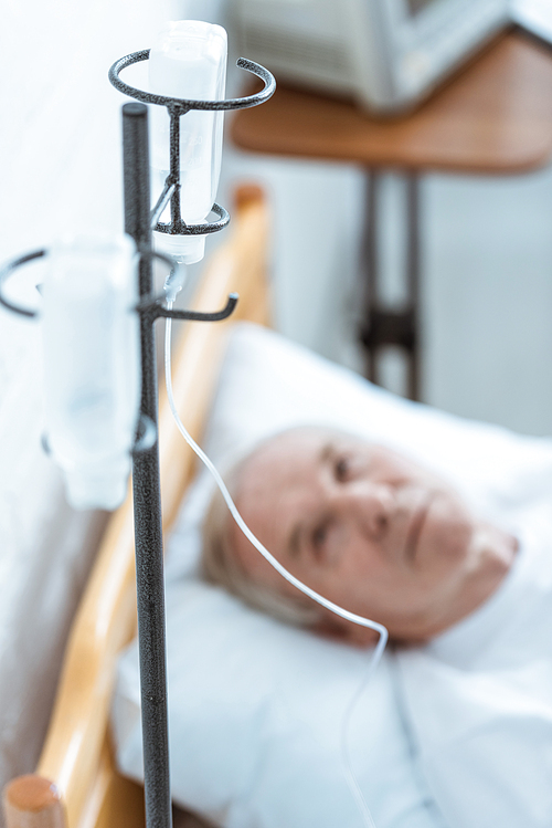selective focus of sick senior man lying on bed in clinic