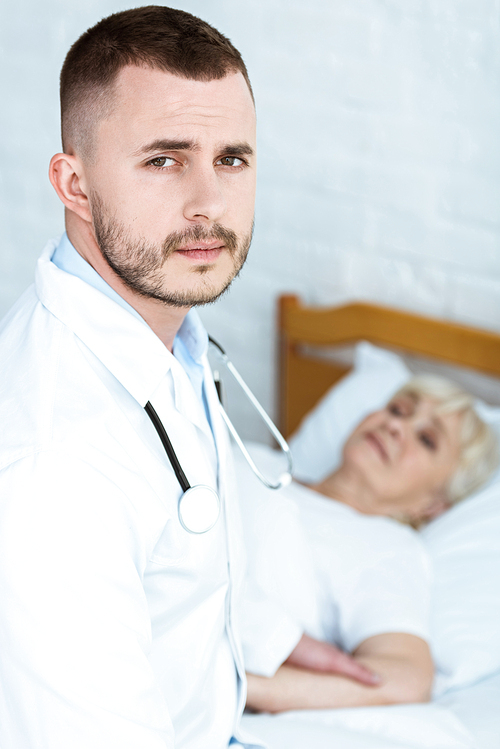 doctor in white coat and sick senior patient lying on bed