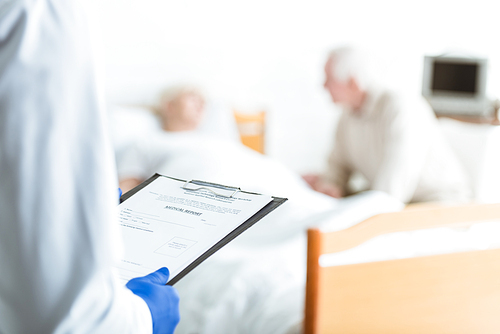 partial view of doctor holding clipboard, ill patient and senior man in clinic