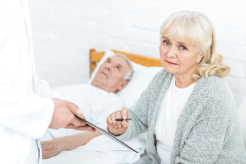 cropped view of doctor with clipboard, senior woman and ill patient