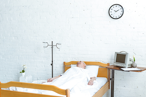 senior patient lying on bed in hospital ward