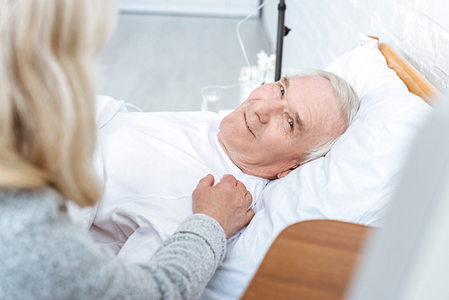 partial view of senior woman and smiling ill man in clinic