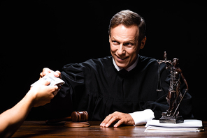 cropped view of woman giving bribe to judge isolated on black