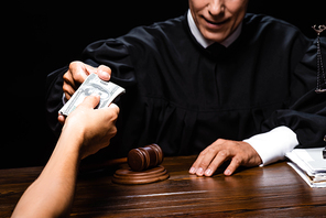 cropped view of woman giving bribe to judge isolated on black