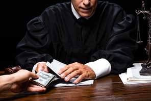 cropped view of woman giving bribe to judge isolated on black