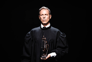 judge in judicial robe holding themis figure isolated on black