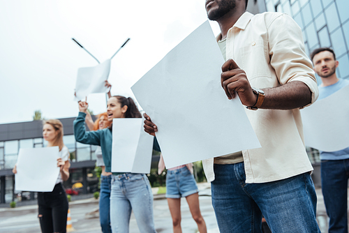 cropped view of african american man holding empty broad near girls and man on street