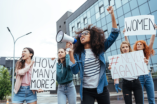 selective focus of african american girl gesturing while holding megaphone near girls on meeting