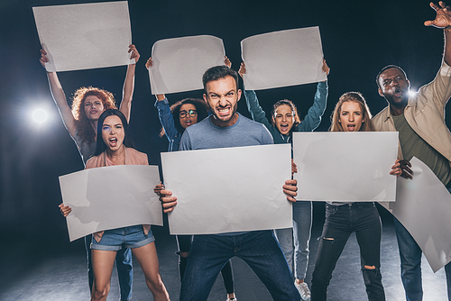 emotional multicultural men and women with blank placards on black