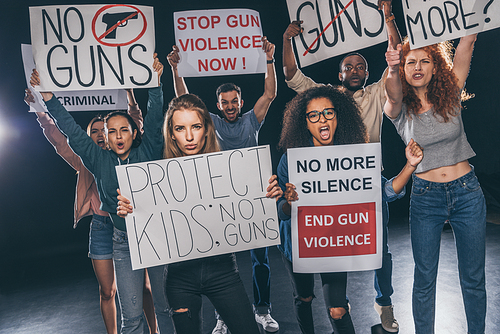 emotional multicultural people screaming while holding placards with lettering on black