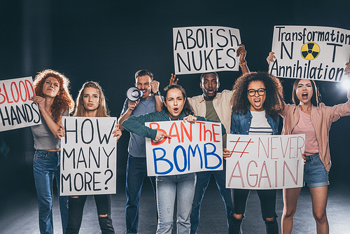 emotional multicultural men and women holding placards with letters on black