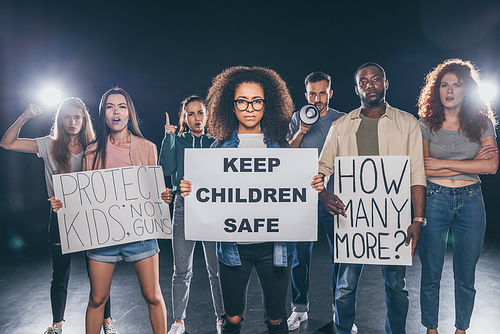 african american woman holding placard with keep children safe lettering near group of people on black