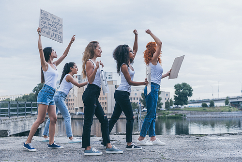 emotional multicultural girls holding placards and screaming while walking outside