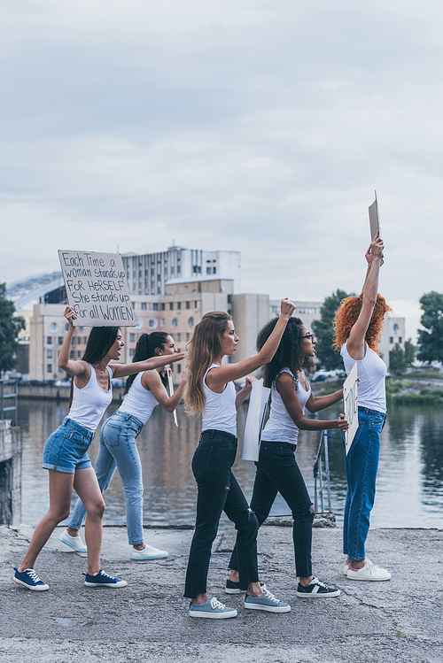 multicultural girls holding placards and screaming while walking outside