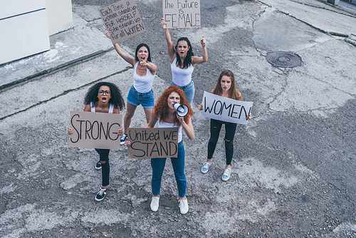 overhead view of multicultural girls holding placards and screaming outside