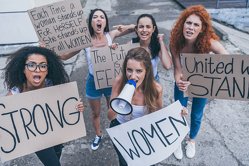 beautiful multicultural girls holding placards and screaming outside