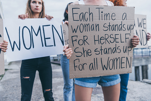 selective focus of girl holding placard with each time a women stands up for herself sh stands up for all women letters