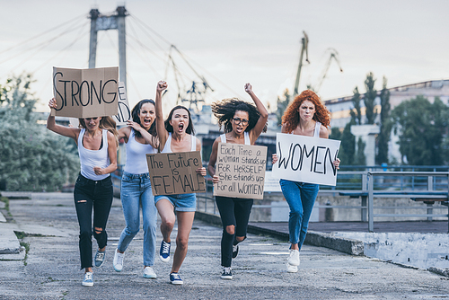 emotional multicultural women holding placards and running outside