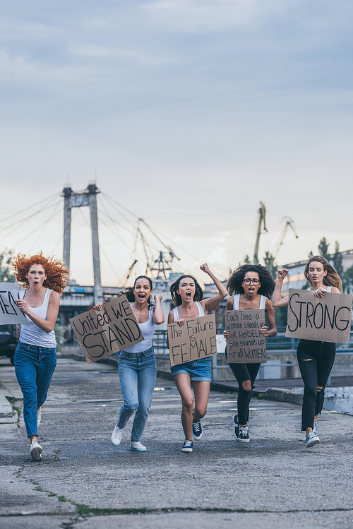 multicultural women holding placards and running outside