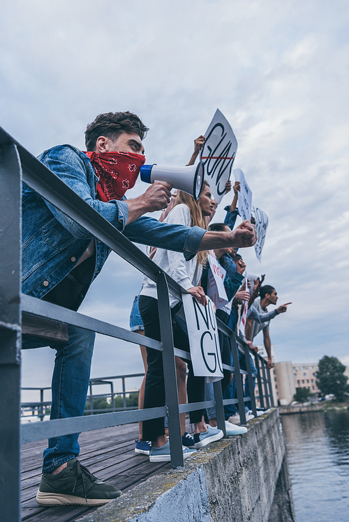 low angle view of man holding megaphone near multicultural people with placards