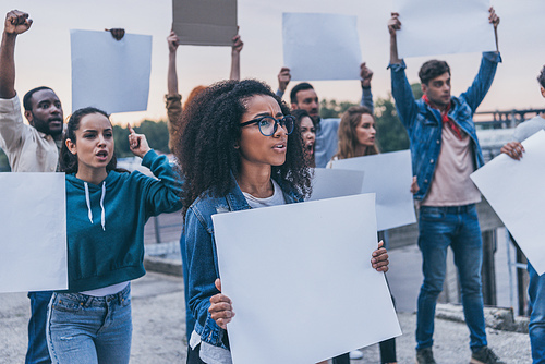 selective focus of emotional multicultural girls holding blank placards