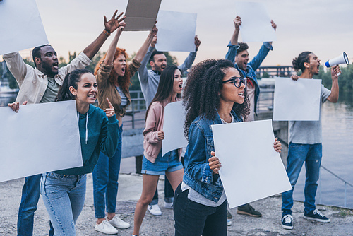 selective focus of emotional multicultural people holding blank placards